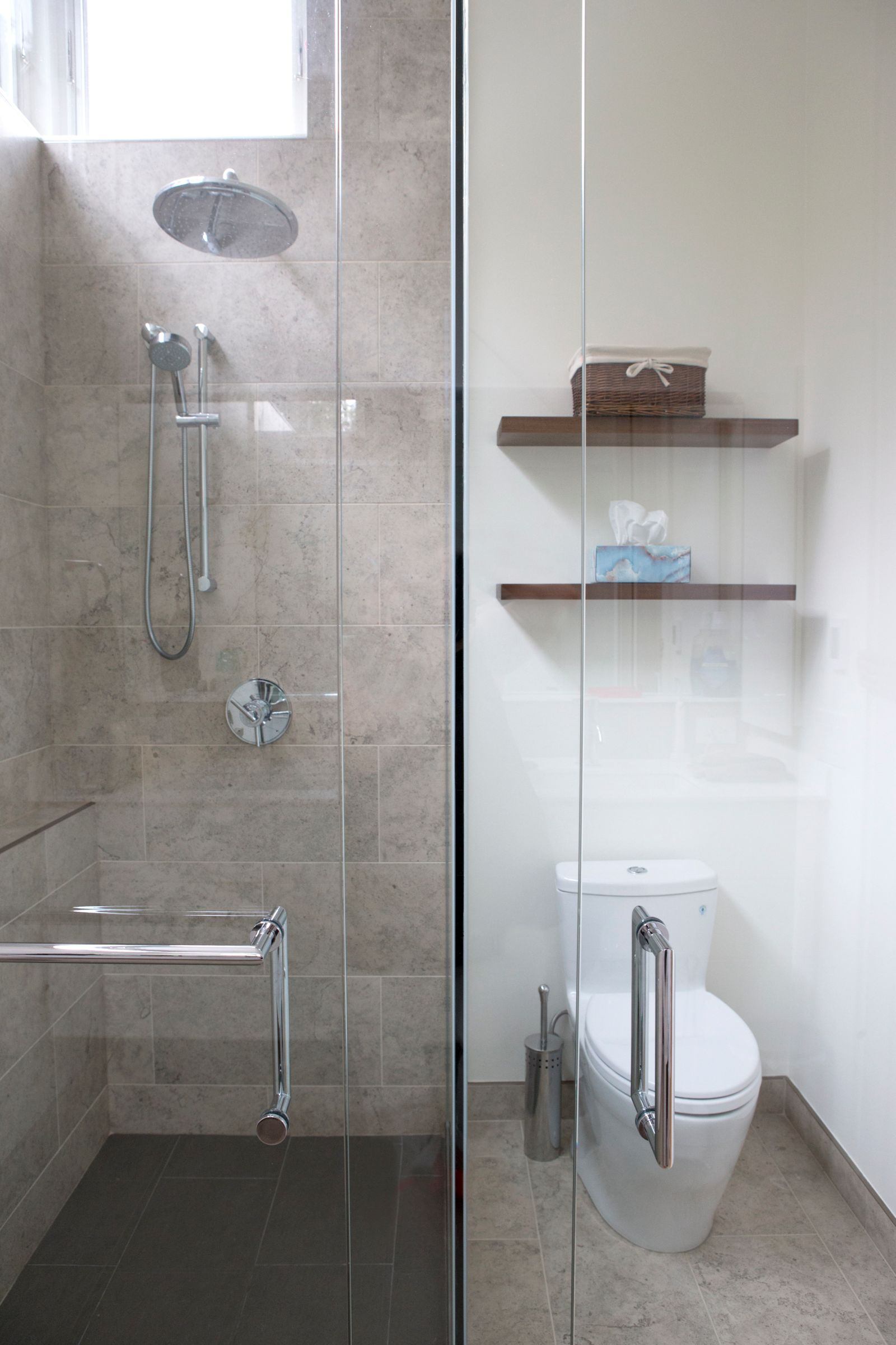 Walk-in shower behind glass door with large floor tiling